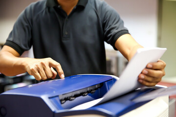 Technician hand press button and load paper in tray to using photocopier for scanning fax or photocopy or copy document after repairing paper jam or change toner cartridge in office workplace.
