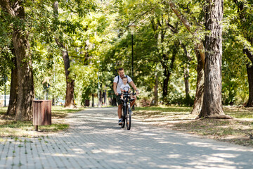 A happy father and son riding a bike in park on earth's day.