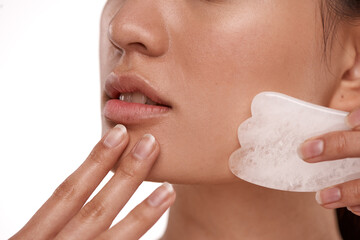 For smoother, firmer skin. Shot of a beautiful woman using a Gua Sha tool on her face.