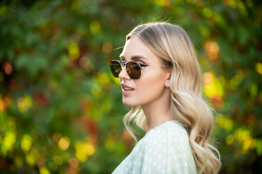 Portrait of a young woman in sunglasses, close up face of beautiful woman outdoor. Cheerful female model.