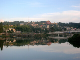 Fototapeta na wymiar The small hill town mirrored at Sumendu Lake look mesmserizing at Mirik in Darjeeling. This is an old artificial lake measuring around 1.25 km long and main attraction of the place.