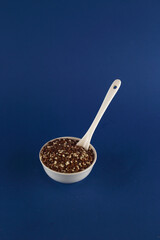 bowl of beniseed and linseed mix and spoon isolated on blue background flat lay