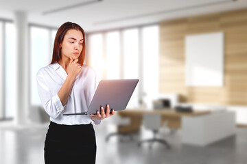 Young attractive businesswoman wearing formal suit is holding la