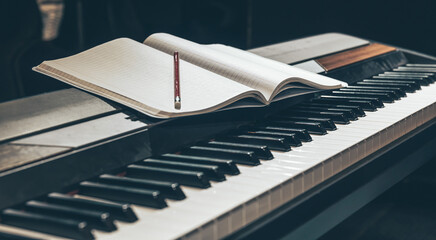 Open notepad on piano keys in the dark, close up.