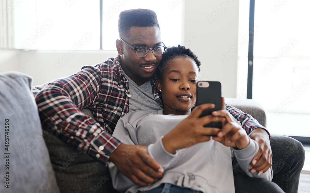 Poster Couch time connections. Shot of a young couple using a cellphone while relaxing on a sofa at home.