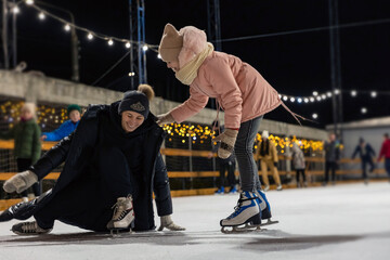 mother and daughter are skating, mother has fallen and is trying to get up