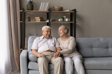 Happy strong marriage, pure love and understanding between older spouses concept. Smiling senior wife and husband rest on couch talking, laughing, enjoy conversation and untroubled life on retirement