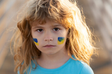 No war, stop war, russian aggression. Ukraine flag on kids cheek. Close up kids face.