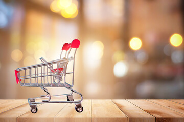 Shopping cart on wooden table in bokeh background.