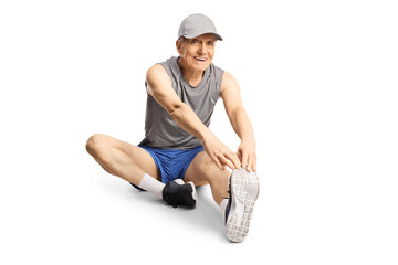 Elderly man in sportswear stretching his leg and sitting on the floor