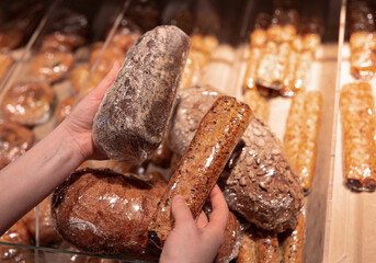 A woman holds bread in her hands at the supermarket counter.