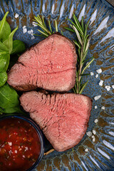 Delicious, Juicy grilled piece of grilled steak with spinach and sauces on a glossy blue plate.