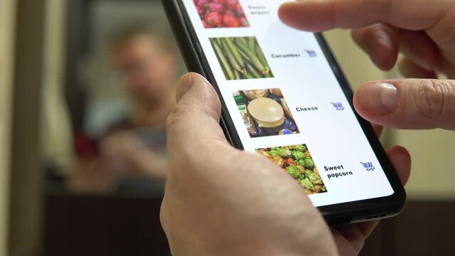 A man stands in front of a mirror in the bathroom and scrolls through the assortment of products in an online store.
