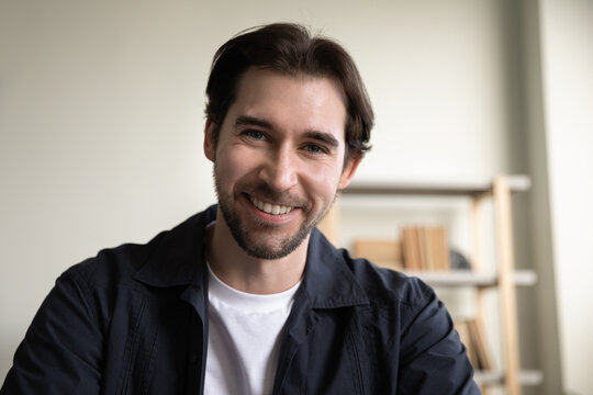 Happy handsome young guy in casual video call head shot portrait. Millennial business man looking at web cam, speaking at gadget camera with toothy smile. Communication concept. Screen view