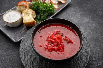 Ukrainian borsch with donuts, sour cream and dill, on a dark background