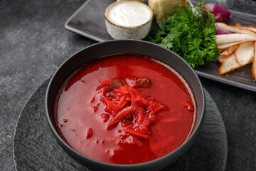 Ukrainian borsch with donuts, sour cream and dill, on a dark background