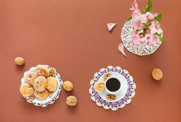 Morning still life with a cup of black coffee and appetizing homemade snail-shaped buns on lacy napkins on a brown table. Homemade cake for breakfast or snack. Flat lay, copy space, top view, close up