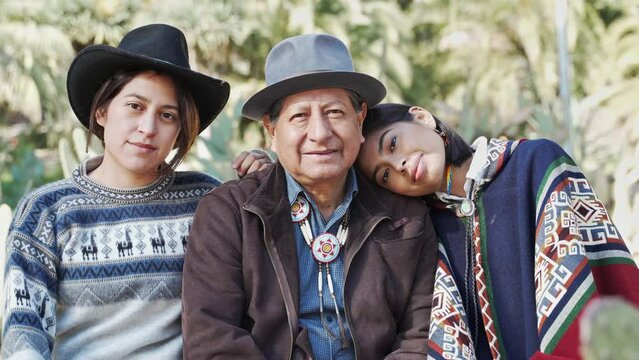 Latin American Indigenous Quechua Senior Father With Two Young Sister Daughters Wearing Poncho From Ecuador. Portrait Of A Native American Family With Traditional Clothes 