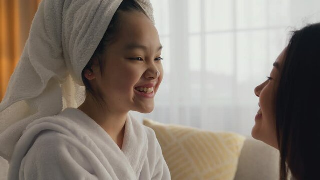 Family connection. Loving asian mother touching nose and caressing face of her cute little daughter, slow motion
