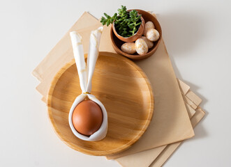 Top view flat lay egg with bunny ears on wooden plate serving for easter celebration.