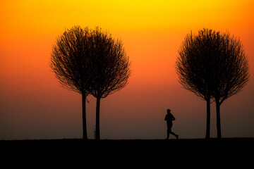 silhouette of runner against orange sky during sunset