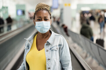 Portrait of african senior passenger waiting inside departure terminal at airport while wearing...