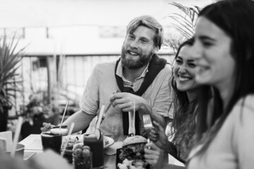 Young people eating brunch and drinking smoothies at healthy food bar restaurant - Focus on man face - Black and white edition