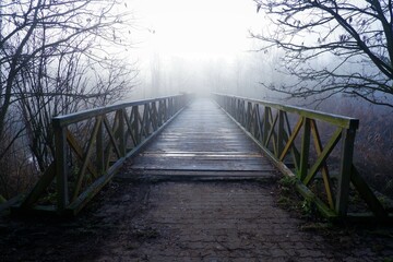 beautiful mystical old wooden bridge in the fog in winter morning dawn in Hungary