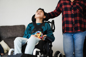 Mother taking care of son with disability on wheelchair at home - Focus on boy face