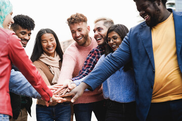 Young diverse team having fun stacking hands outdoor - Focus on asian girl face
