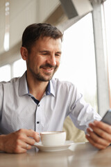 Happy man with phone in cafe