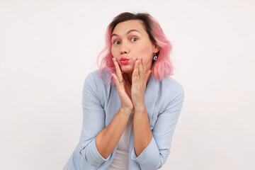 a young woman looks at the camera with interest and surprise, raising her eyebrows and looking silly, standing on a white background.