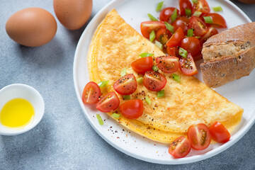 Middle close-up of omelette served with fresh cherry tomatoes on a white plate, horizontal shot