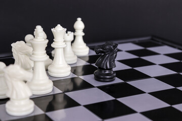 The king in a battle chess game stands on a chessboard with a black isolated background. Business Leadership Ideas.