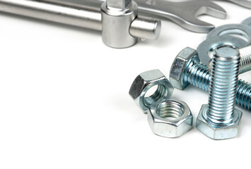 Several silver metal fixing bolts on a white background.Metal bolts and nuts. Wrenches for working with bolts and nuts. Close-up. copy space