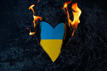 The symbol of the national flag of Ukraine burns on a black background. Love Ukraine concept or war concept.