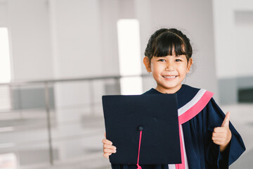 Portrait of a cute Asian graduated schoolgirl with graduation gown in school