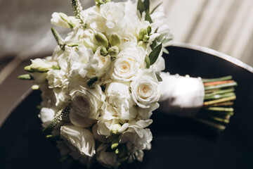 a beautiful wedding bouquet of white flowers and greenery lies on the table