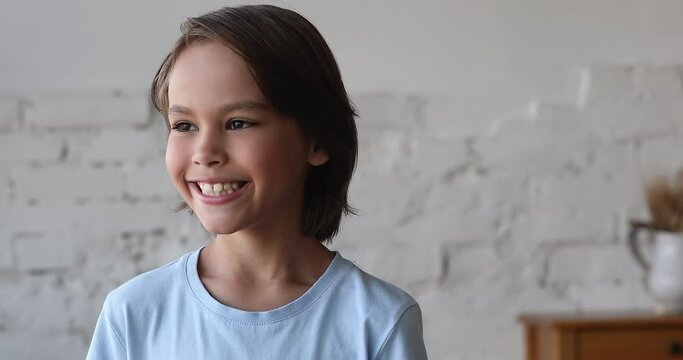 Head shot handsome pre-teen 9s boy smiling looking into distance having wide charming toothy candid smile and attractive appearance. Adorable pre-adolescent child portrait, young generation Z concept