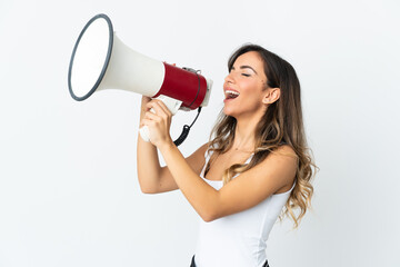 Young caucasian woman isolated on white background shouting through a megaphone to announce something in lateral position