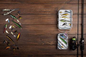 Fishing tackle - fishing spinning rod, hooks and lures on wooden background. Active hobby...