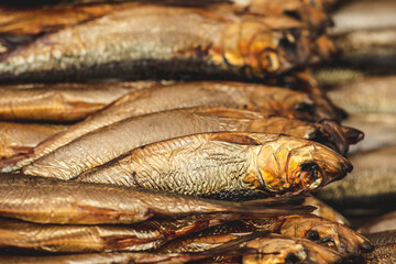 Dry smoked salted herrings in a row in a street food market, close up,