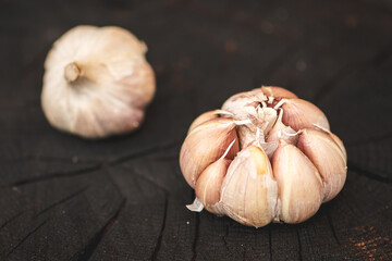 Garlic bulbs and cloves on a black wooden rustic chopping board background, close up 
