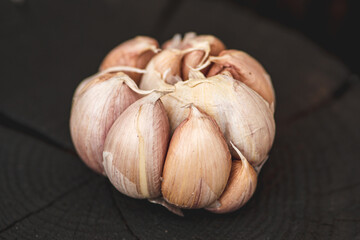 Garlic bulb and cloves on a black wooden rustic chopping board background, close up 