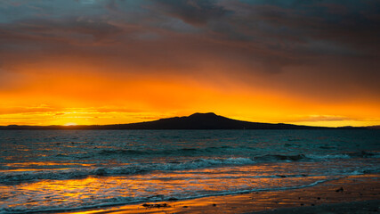 Fototapeta na wymiar Sun rising over the Rangitoto Island, Milford Beach, Auckland.