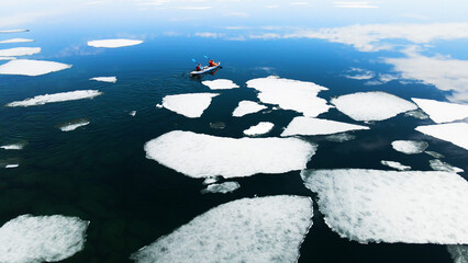Kayak sailing between ice floes on the lake. Aerial drone view. Baikal lake, Siberia, Russia. Spring landscape