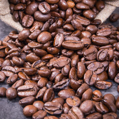 Heap of dark roasted fragrant coffee beans in jute bag