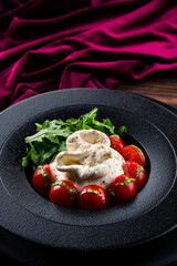 Salad with traditional italian burrata cheese with arugula and tomatoes