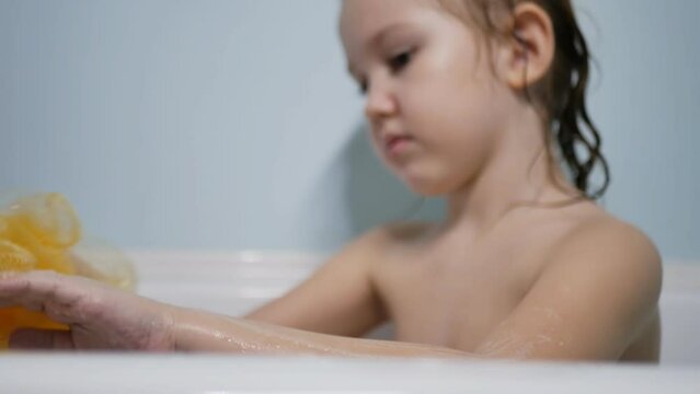 caucasoid teenage girl lathers her hand with a yellow tuft takes a bath, the concept of personal hygiene in adolescents. slow motion.
