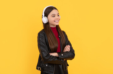 cheerful teen girl listen music in headphones on yellow background, e-learning